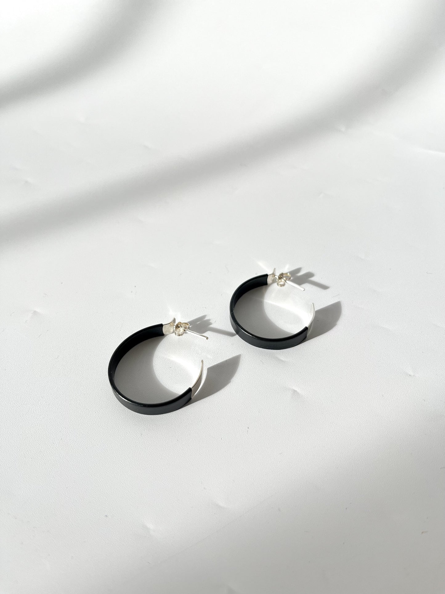 Silver wide hoop earrings with black rubber detail